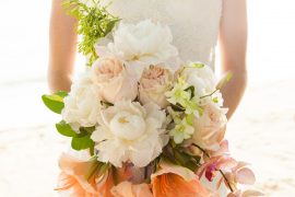 Bride holding bouquet of pink, coral, white, and subtle green wedding florals.