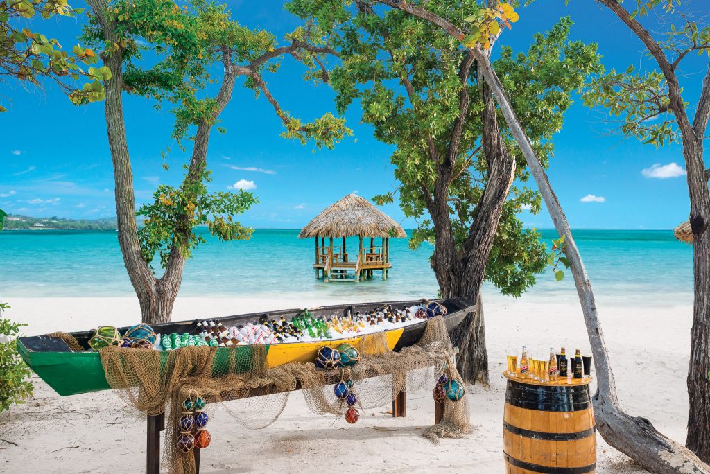 Beer canoe sits on a white-sand beach with turquoise waters in the background