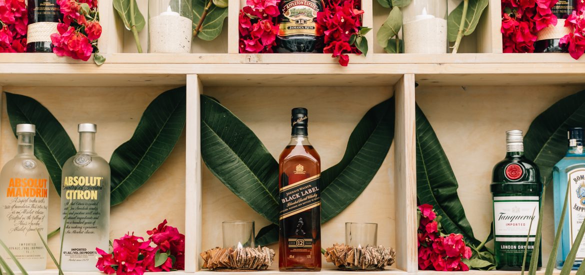 Florals and bottles of premium liquor make up this wedding bar