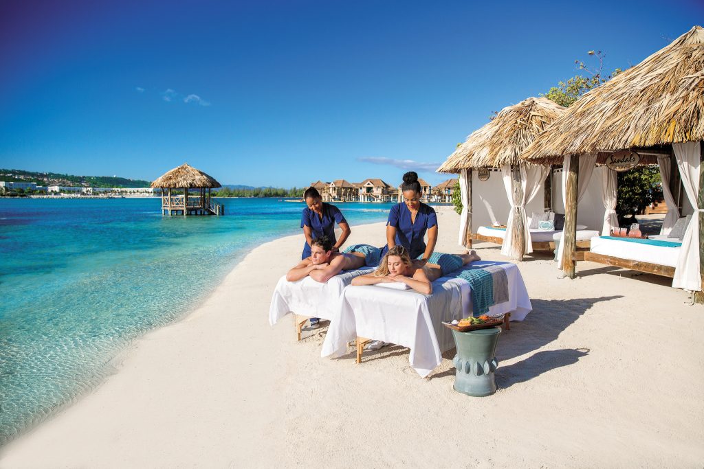 Couple getting a massage on the beach, next to the ocean.