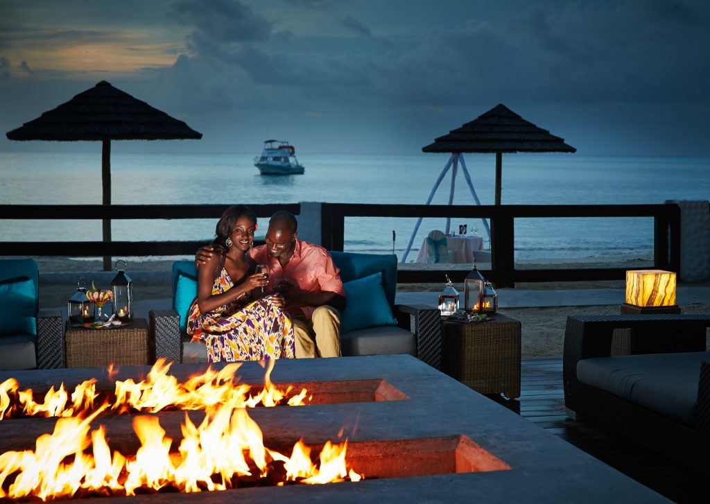 Fire pits are among the best honeymoon ideas for newlyweds! The couple pictured shares a romantic moment, fireside, with wine glasses in hand.