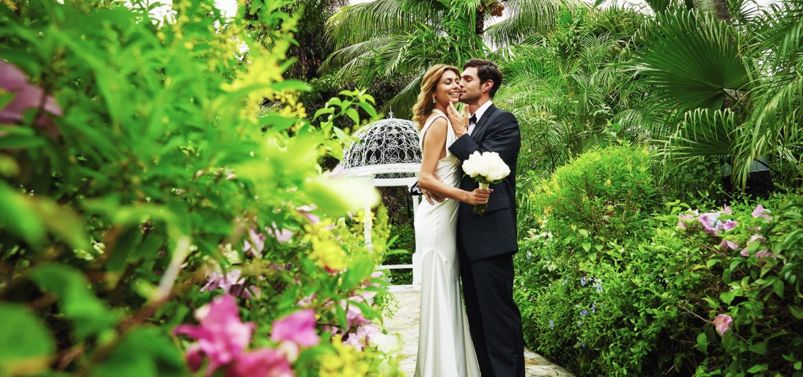 Bride and groom standing in a lush garden setting for photos captured by a destination wedding photographer