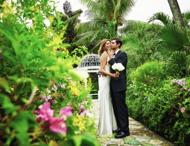 Bride and groom standing in a lush garden setting for photos captured by a destination wedding photographer