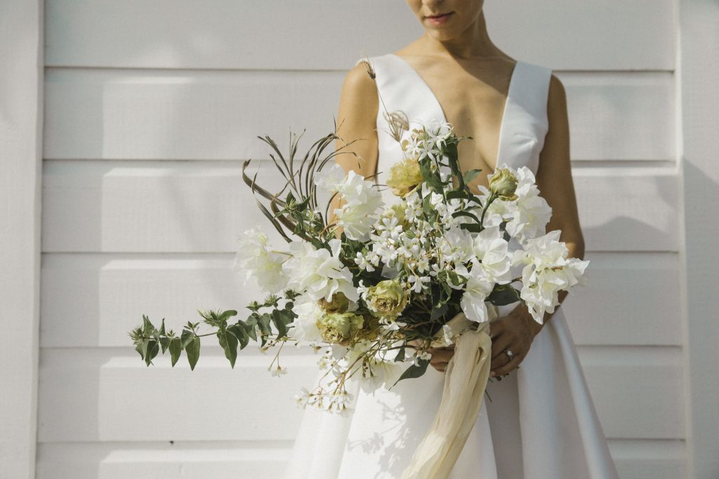 Bride holding beautiful cascading bouquet of natural colored blooms